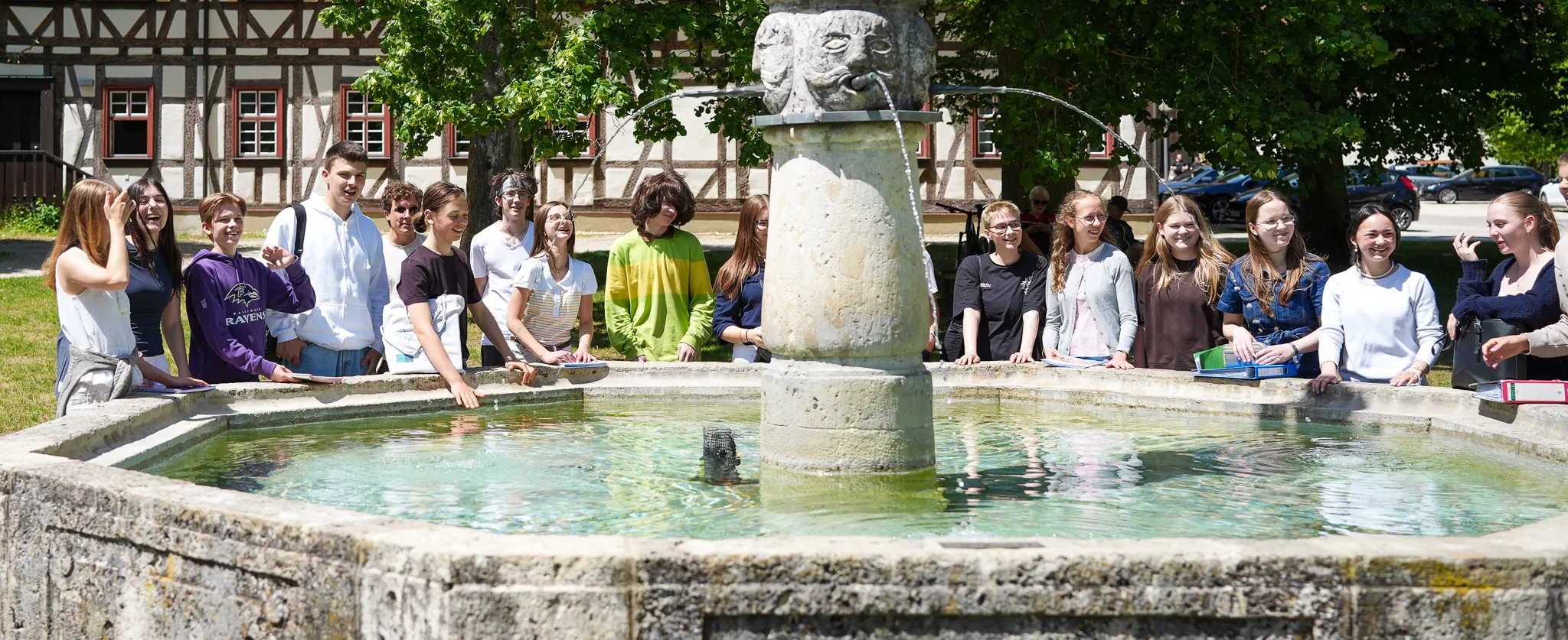 Schülerinnen und Schüler begegnen sich am historischen Johannesbrunnen.