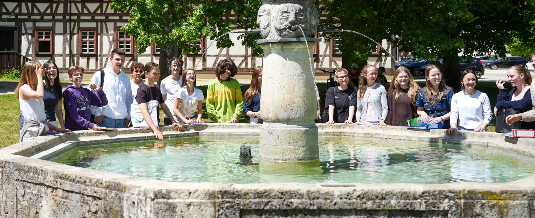 Schülerinnen und Schüler begegnen sich am historischen Johannesbrunnen.